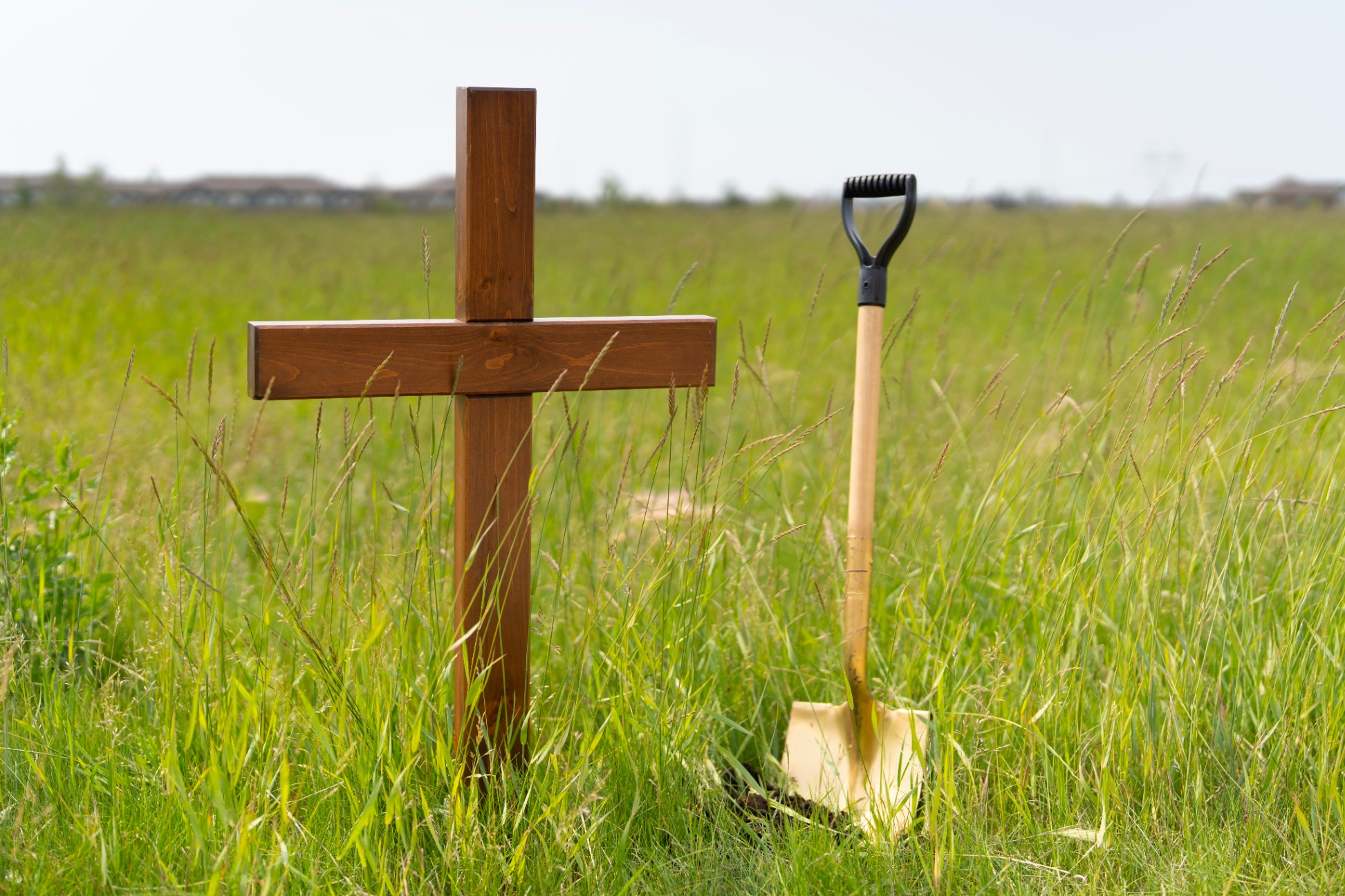 Cross in an empty field, next to ceremonial gold shovel ahead of a Site Blessing for a new school in Hays Ridge