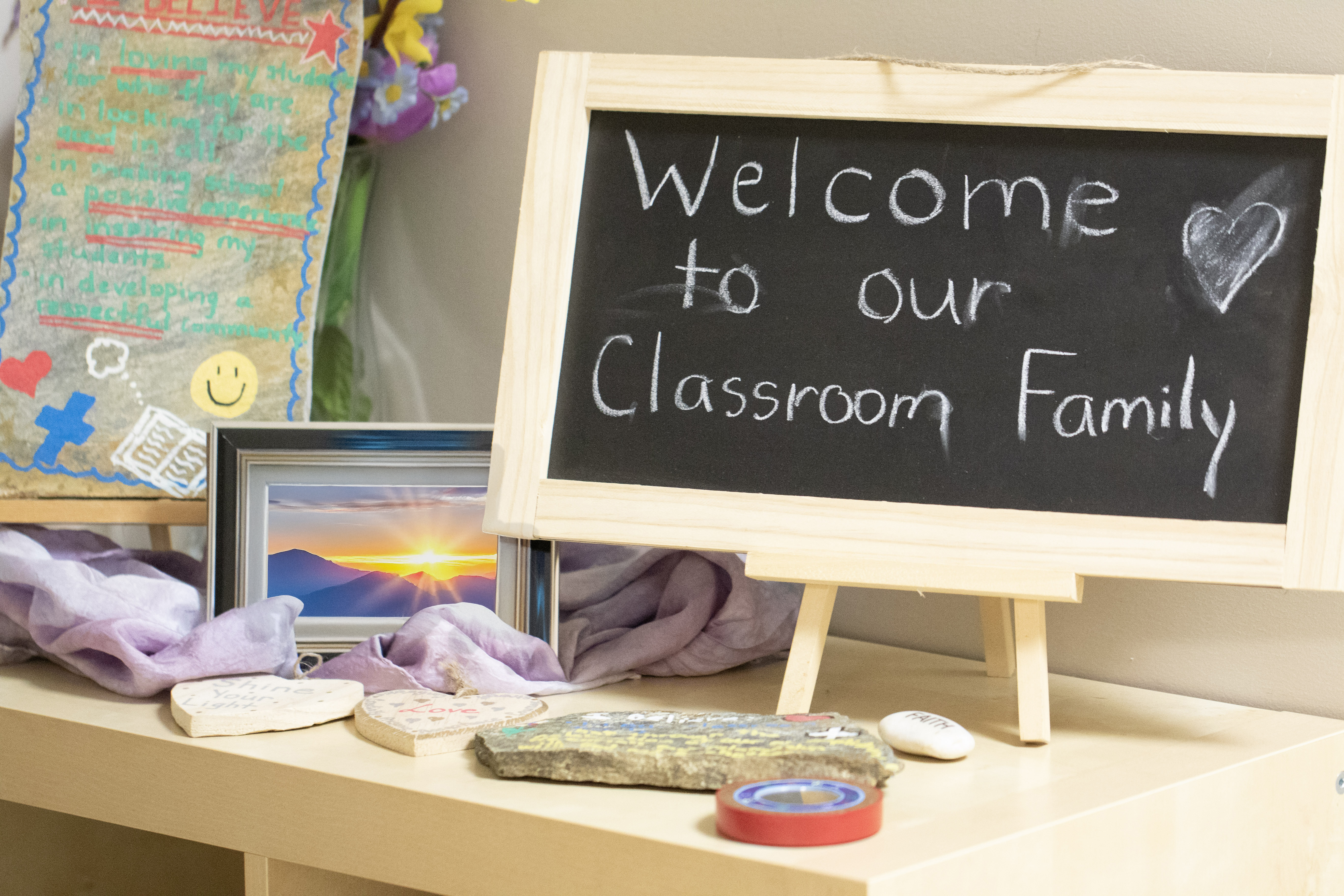 Image that has a photo of teachers in frame, small easel chalkboard that says Welcome to our Classroom Family