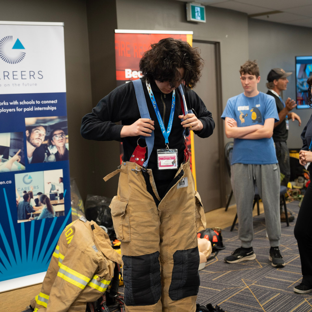 Student participating in careers session_ trying firefighter pants on