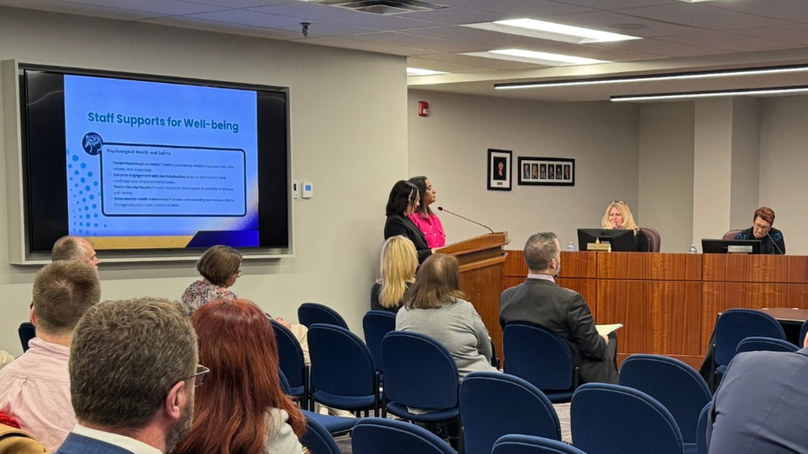 Board meeting with two people at podium presenting