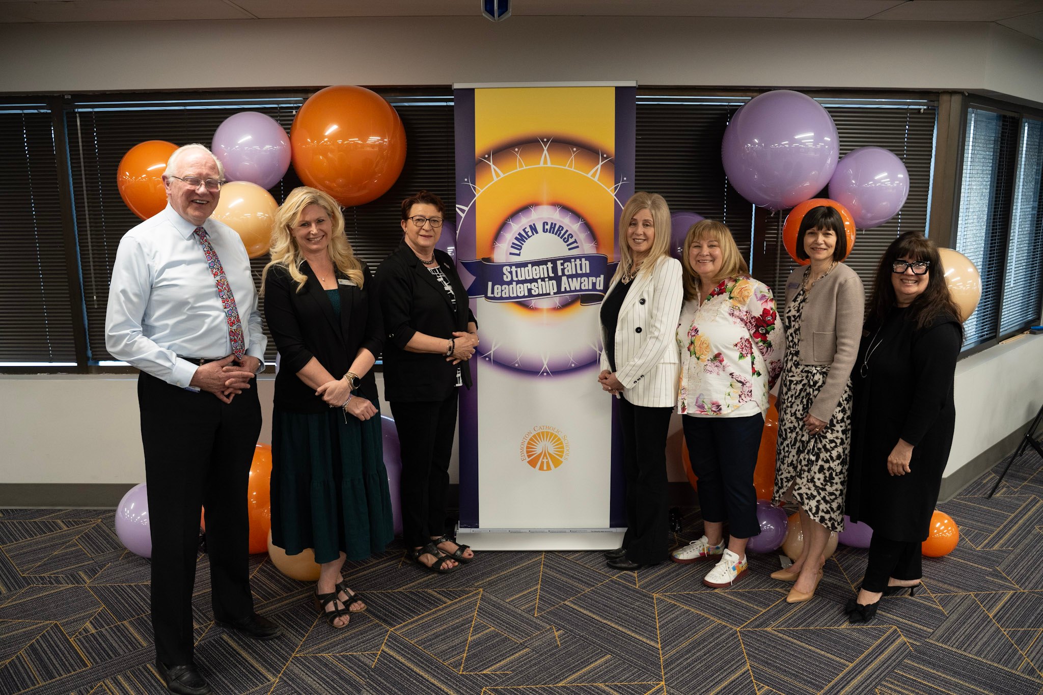 Trustees including Chief Superintendent Lynnette Anderson standing near a pull up banner for Student Faith Leadership Awards.