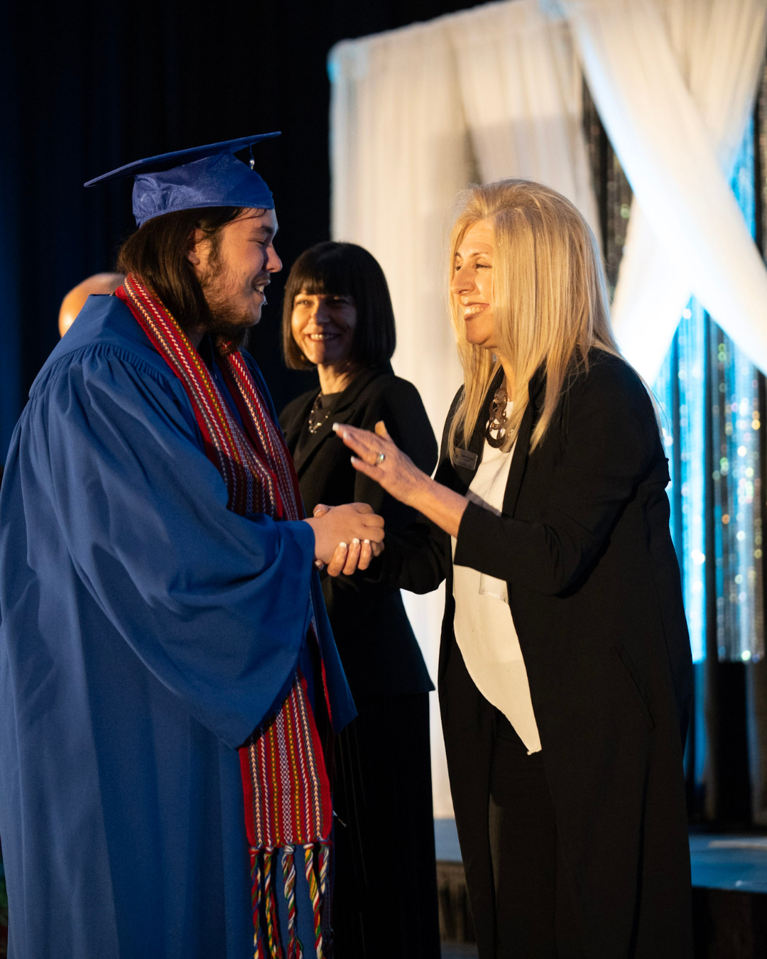 Trustee Palazzo shaking hands with a graduating student in cap and gown